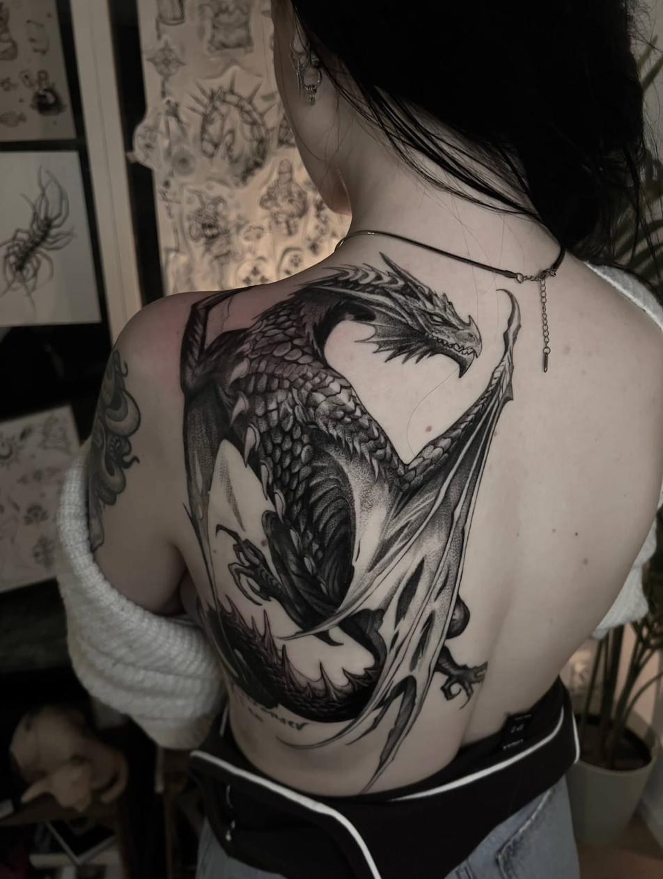 Tattoo artist Uppsala — dragon in blackwork realism on back and shoulder
