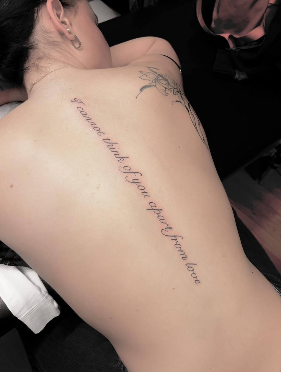 Lettering tattoo Uppsala — quote on back, fine script